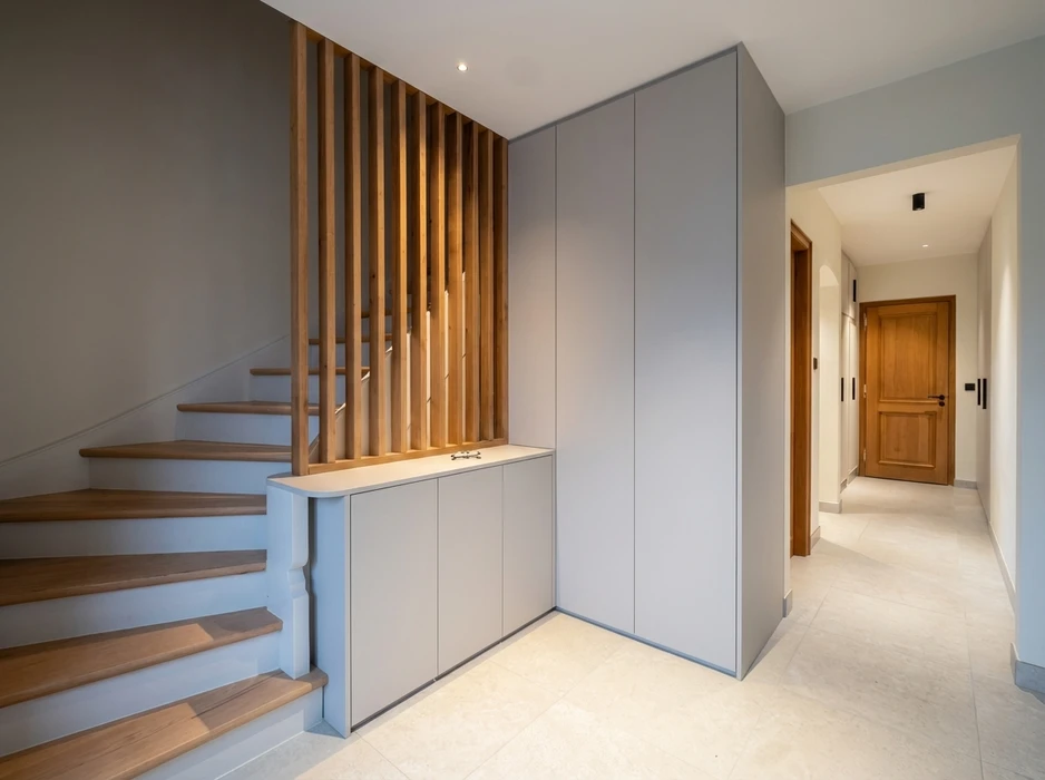 Entrée de maison moderne avec escalier en bois massif et claustra en lamelles de chêne vertical