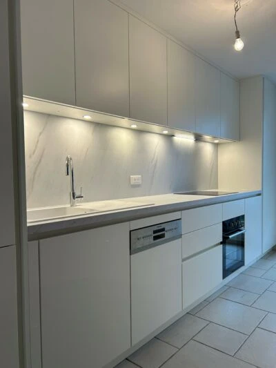 Intérieur moderne avec grande baie vitrée coulissante à deux vantaux, profilés aluminium anthracite, donnant sur une terrasse en carrelage grès cérame grand format