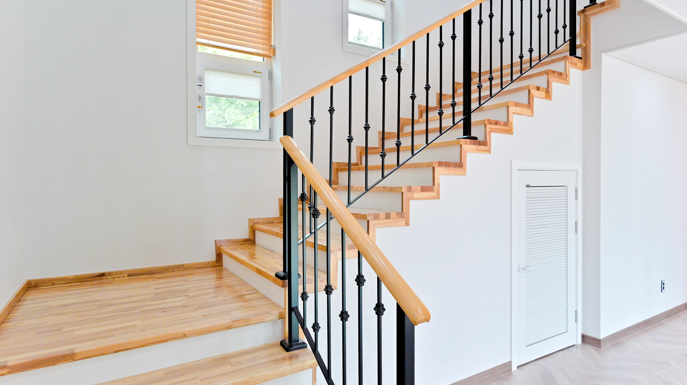 Escalier intérieur résidentiel avec rampe en bois verni et garde-corps en fer forgé ornemental