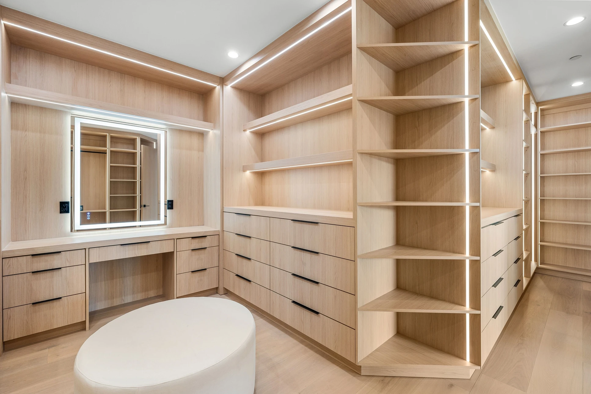 Chambre à coucher moderne avec dressing intégré ouvert, lit double avec tête de lit en bois naturel, parquet clair et mur en marbre blanc veiné